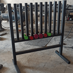 استندی فلزی از پروفیلهای آهنی به رنگ مشکی با دوازده ستون ایستاده که دو پایه بزرگ یرای ایستادن و تعادل دارد که در فواصل ستون ها دمبل های ایروبیک قرار گرفته اند